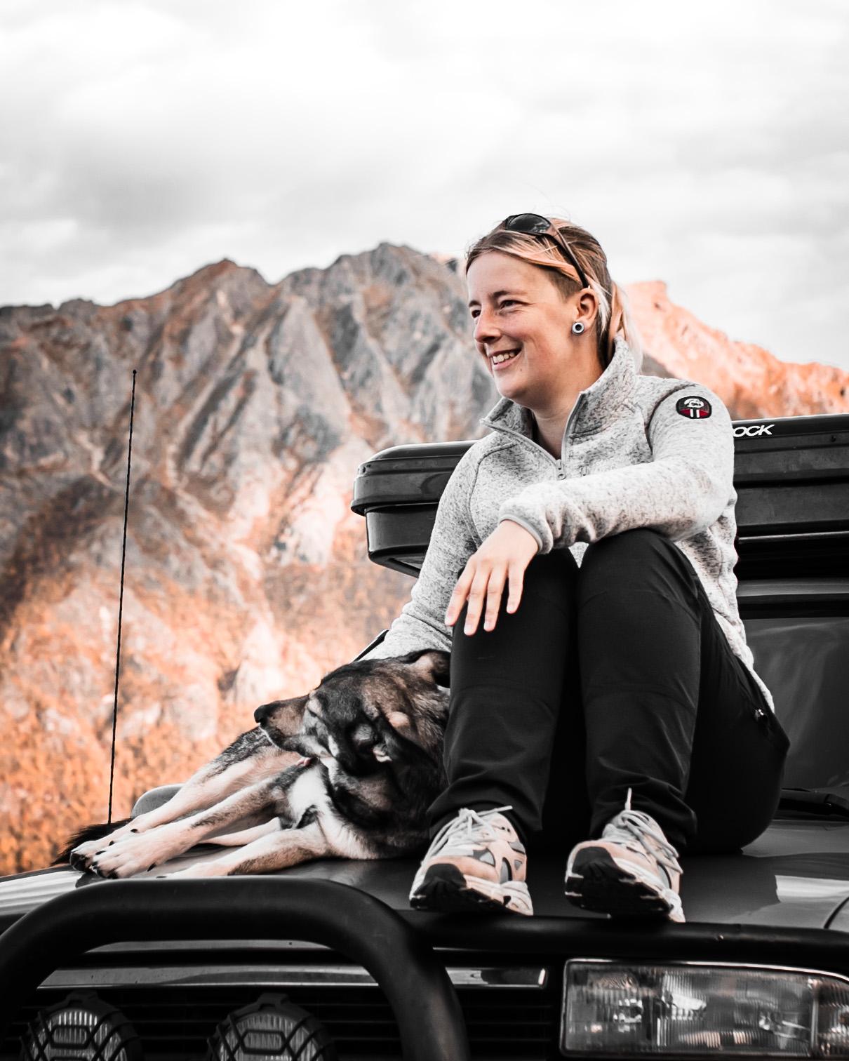 Anne sitting on Chewie with her dog, overlooking the mountains on Lofoten Islands – living the overlanding life.