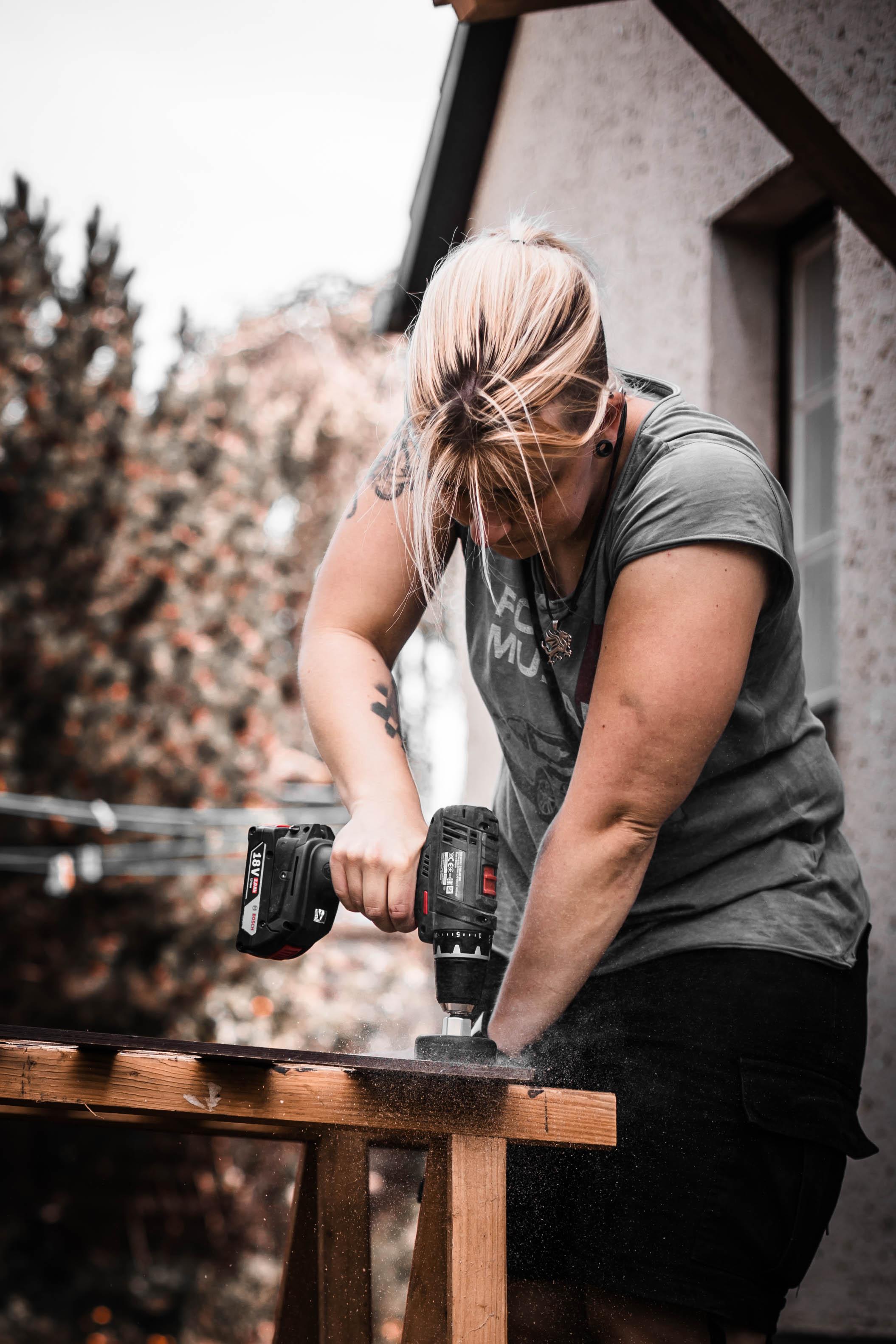 Anne working on her camper build with a power drill, taking full ownership.