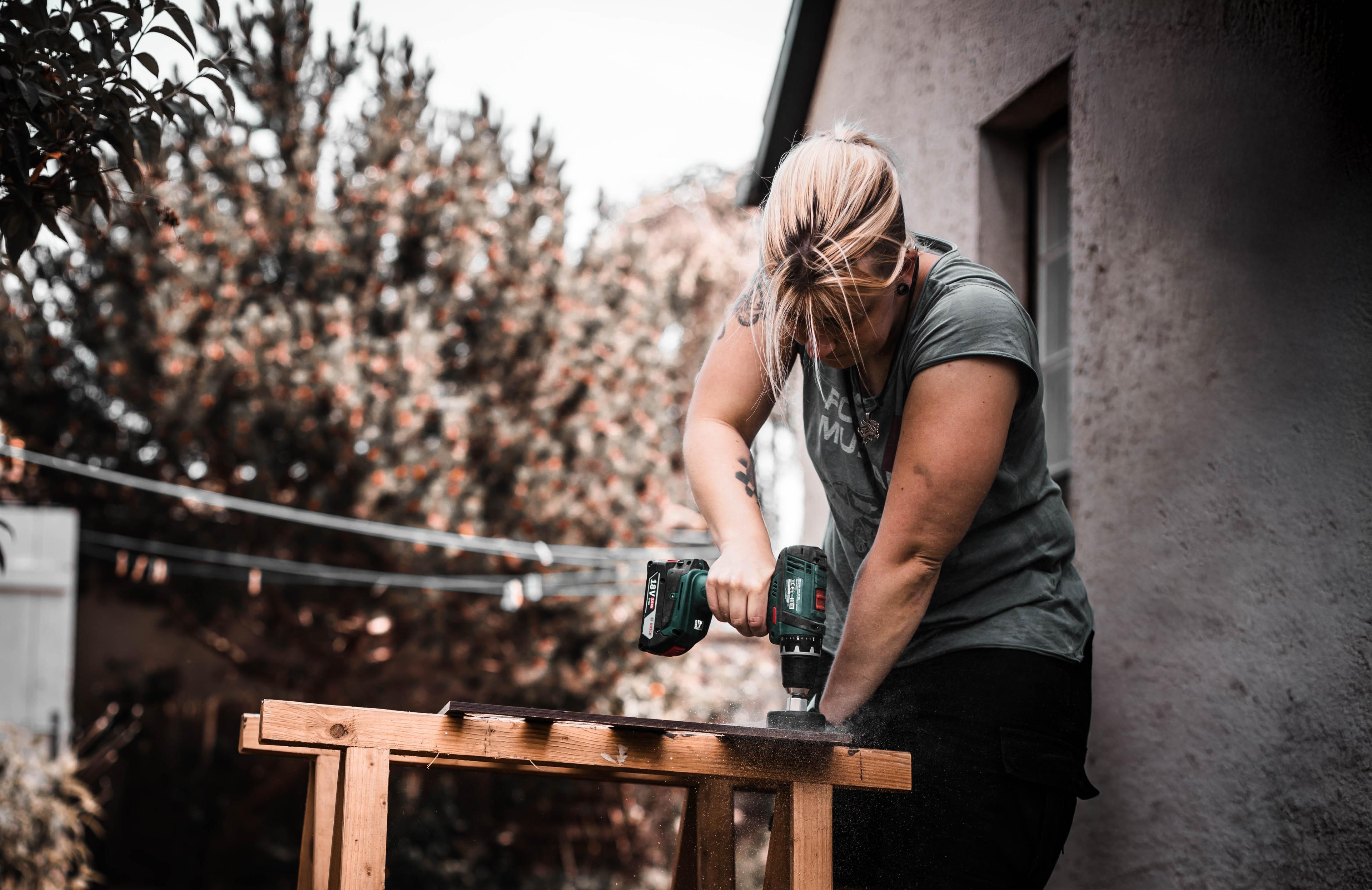 Anne working on her camper build with a power drill, taking full ownership.