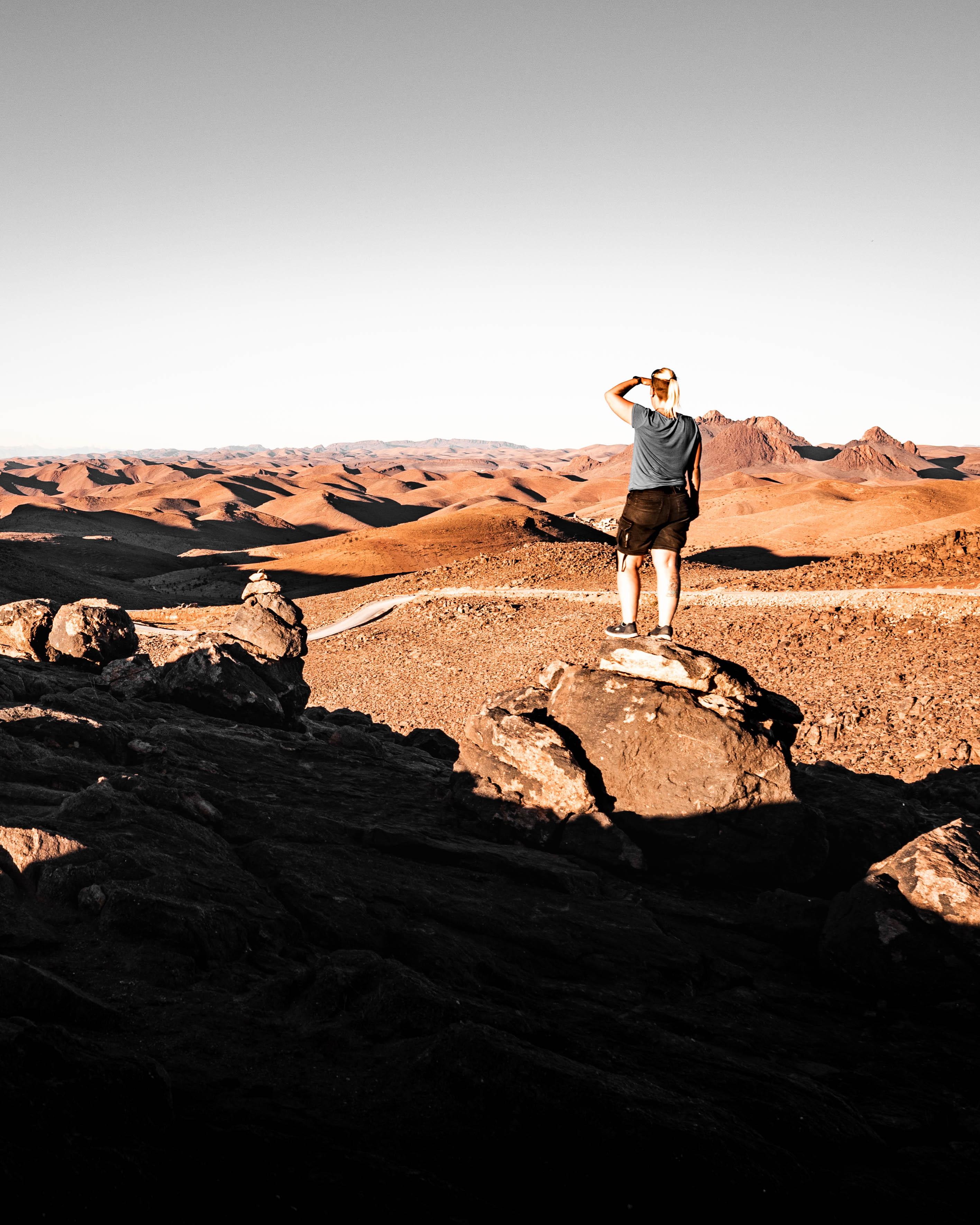 Anne standing on a rock in the Anti-Atlas mountains in Morocco, overlooking a wide rugged landscape that reflects the Terrain Check theme.