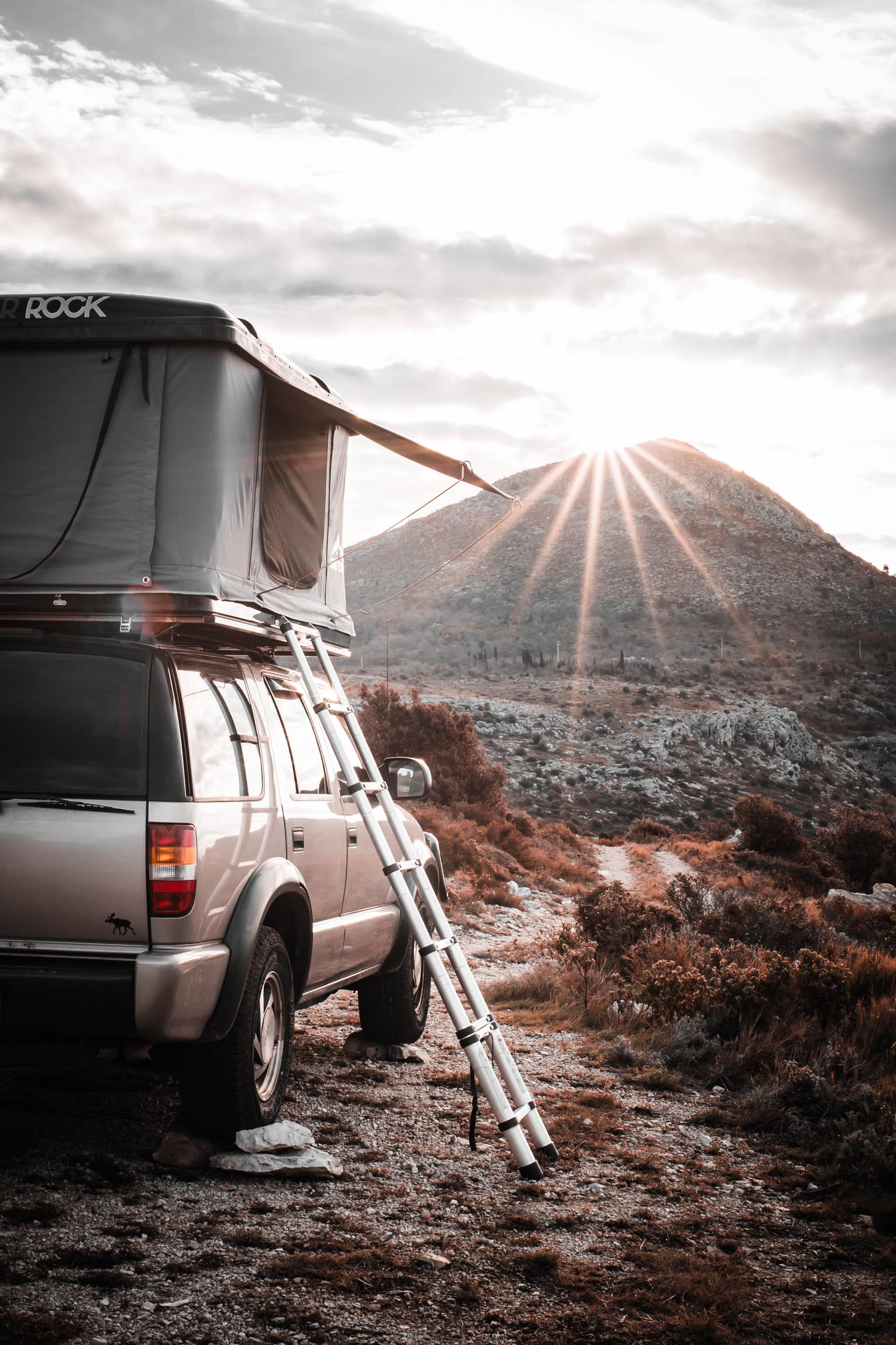 Chevy Blazer with rooftop tent facing a rocky trail at sunrise, ready to see what’s ahead.
