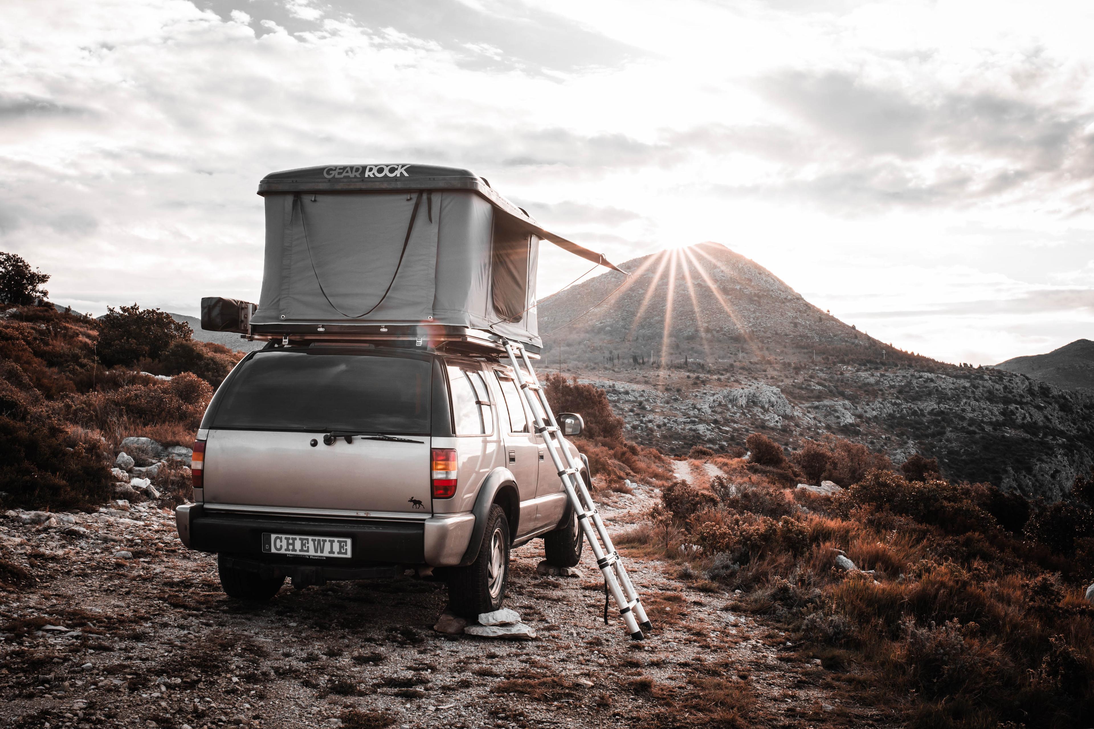 Chevy Blazer with rooftop tent facing a rocky trail at sunrise, ready to see what’s ahead.