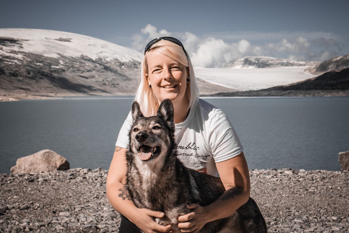 Anne with her dog on a glacier lake, Norway, representing experience with navigating real terrain and complex AppSec programs.