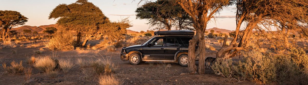 AppSec built from the road TO1999 Chevy Blazer parked beneath an acacia tree at sunset in Morocco, reflecting AppSec built from the road.DO